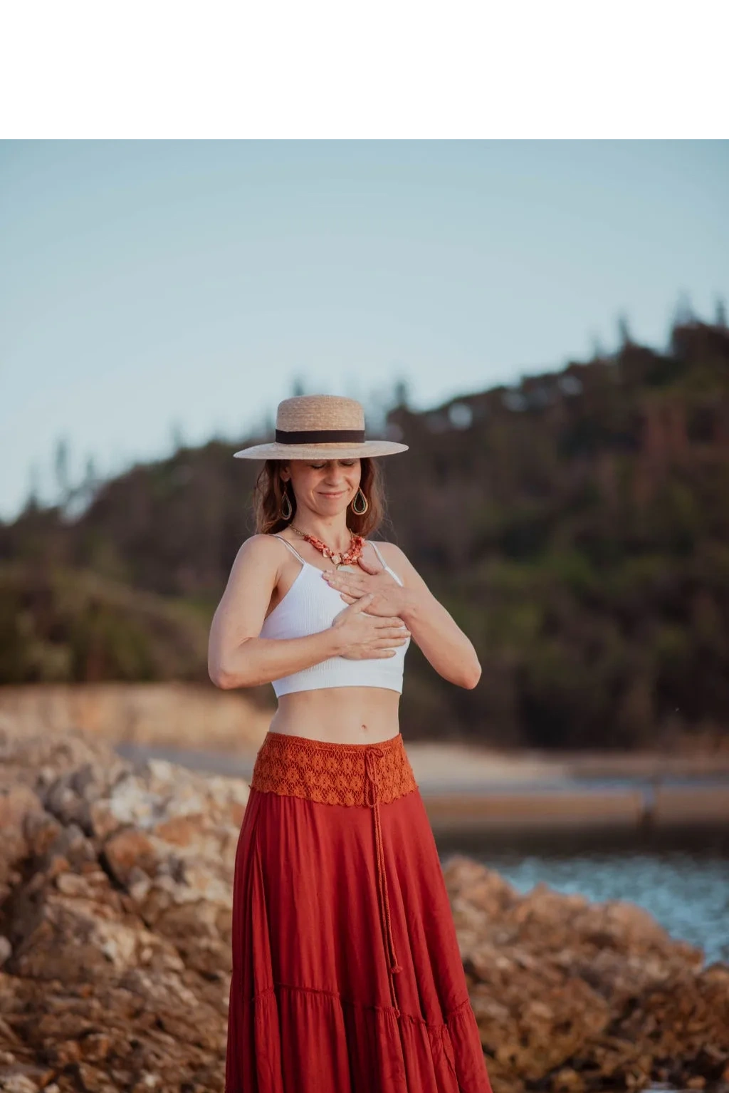 Woman on rocky beach in white and red